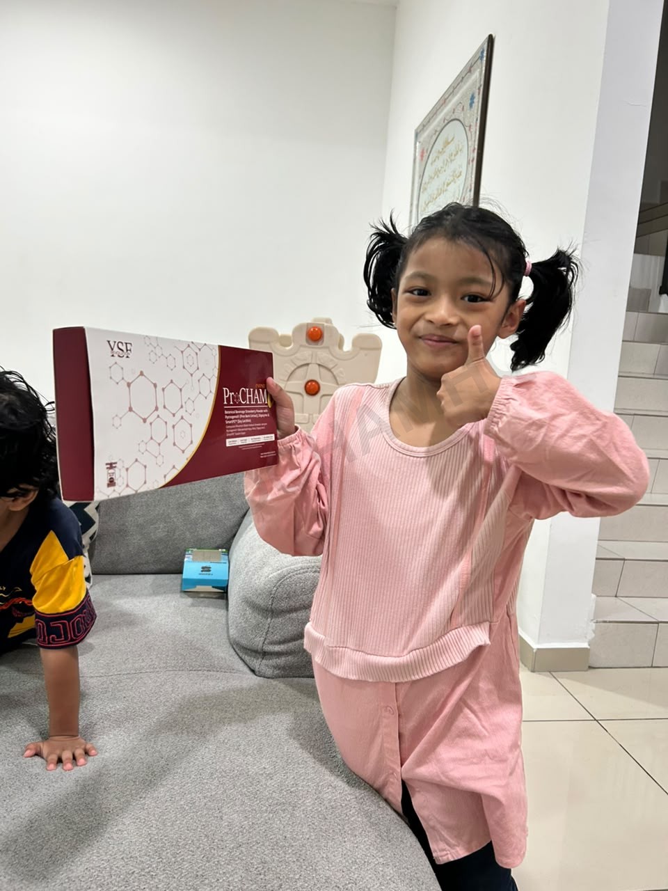 Anak perempuan buat thumbs-up memegang kotak ProCHAM Infinity